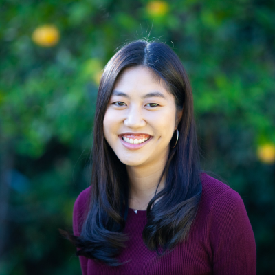 Taryn in front of a blurred green background with yellow flowers