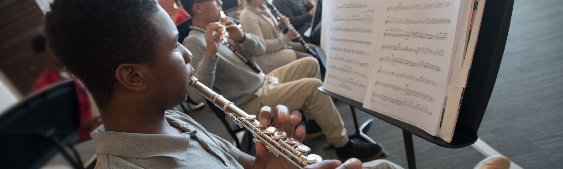 A high school student plays flute with his classmates during music class.
