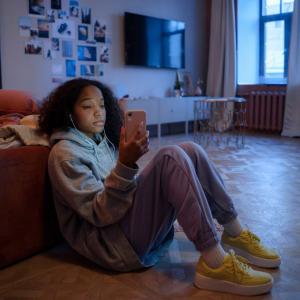 Middle school student sits on the floor near her bed reflecting on how the pandemic impact her social emotional learning and adolescent development