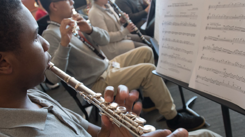 A high school student plays flute with his classmates during music class.